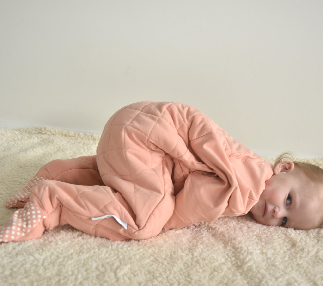 Sleepy toddler wearing a dusty pink quilted toddler onesie for Winter sleep