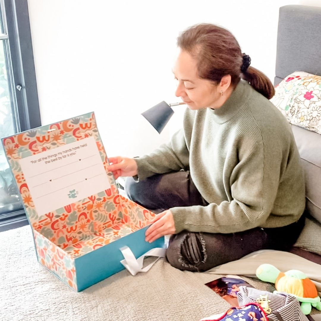 Mother opening a colorful baby memory keepsake box with a floral design.