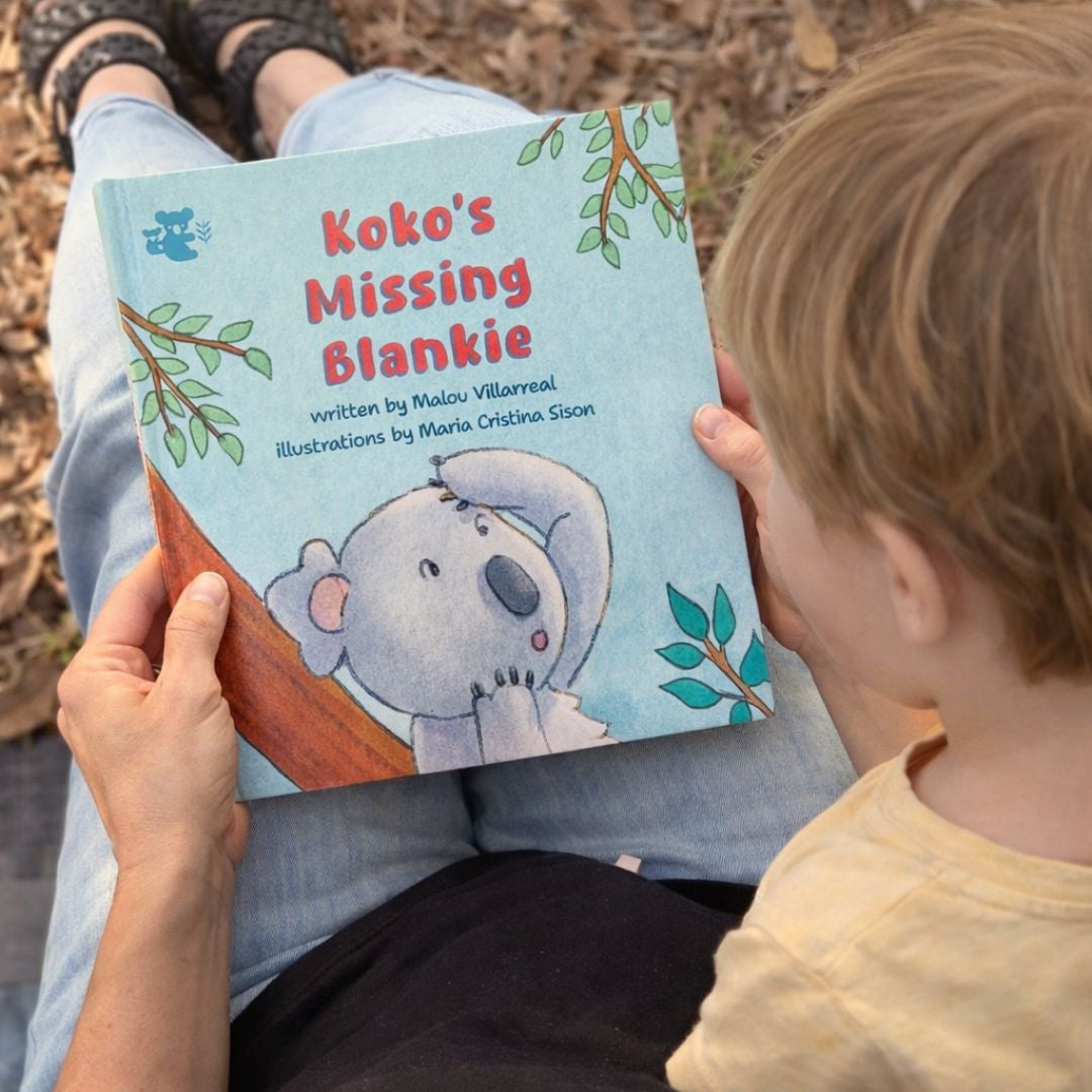 Child reading a book titled 'Koko's Missing Blankie' with a koala illustration on the cover.